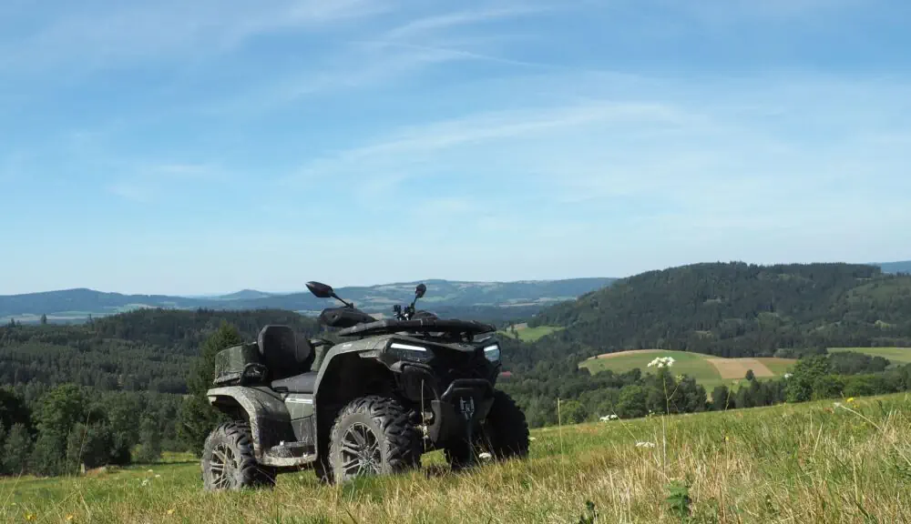 Zaparkowany quad na wzgórzu z rozległym widokiem na góry podczas rekreacyjnej wycieczki na quadach w Kotlinie Kłodzkiej.